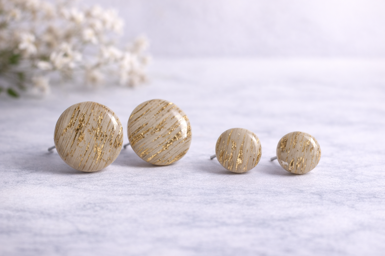 Beige runde Ohrstecker aus Polymer Clay mit goldenen Akzenten, handgefertigt, getragen am Ohr